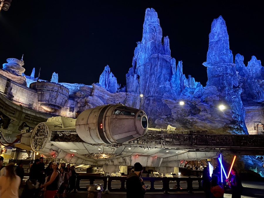 Guests with lightsabers in front of the Millennium Falcon